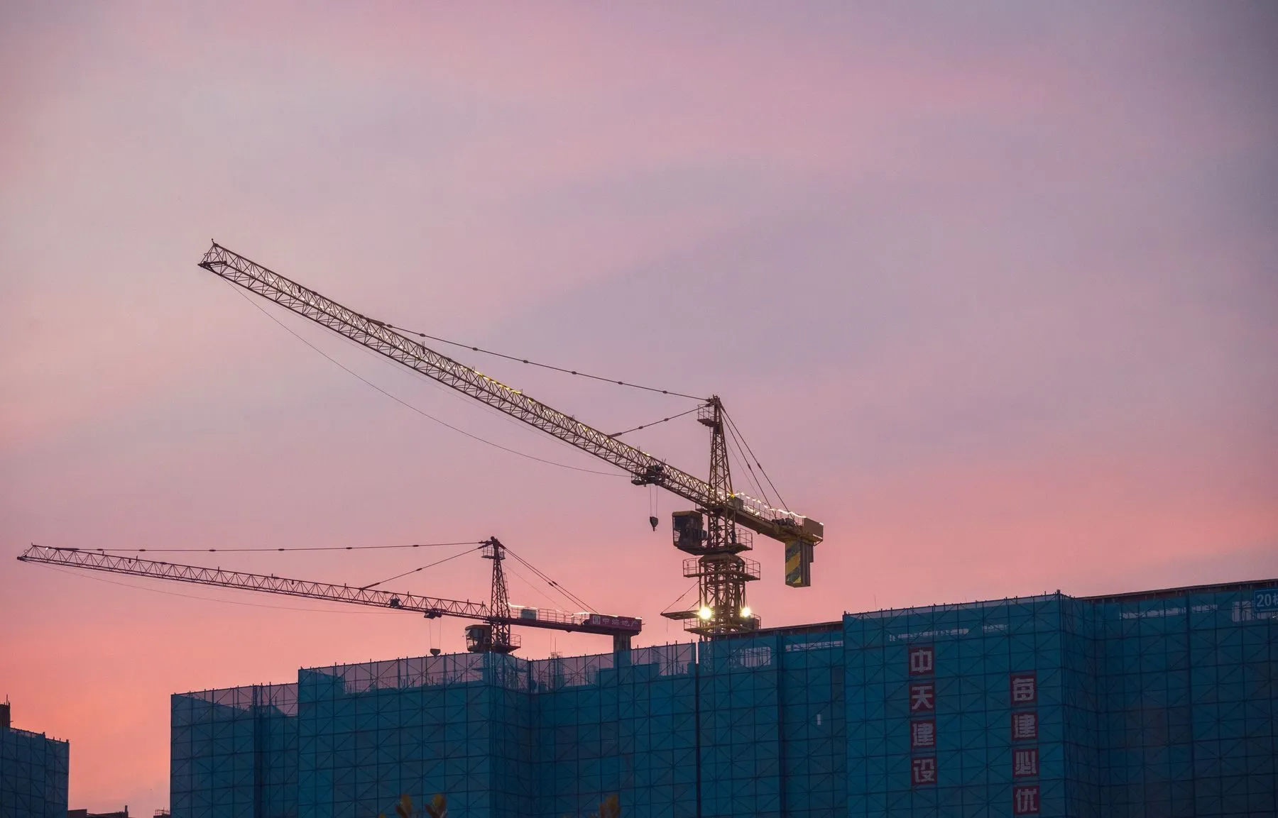 Tower cranes on a residential construction site at sunset